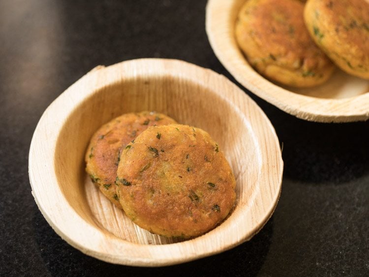 two fried aloo tikkis each placed in two serving bowls. 