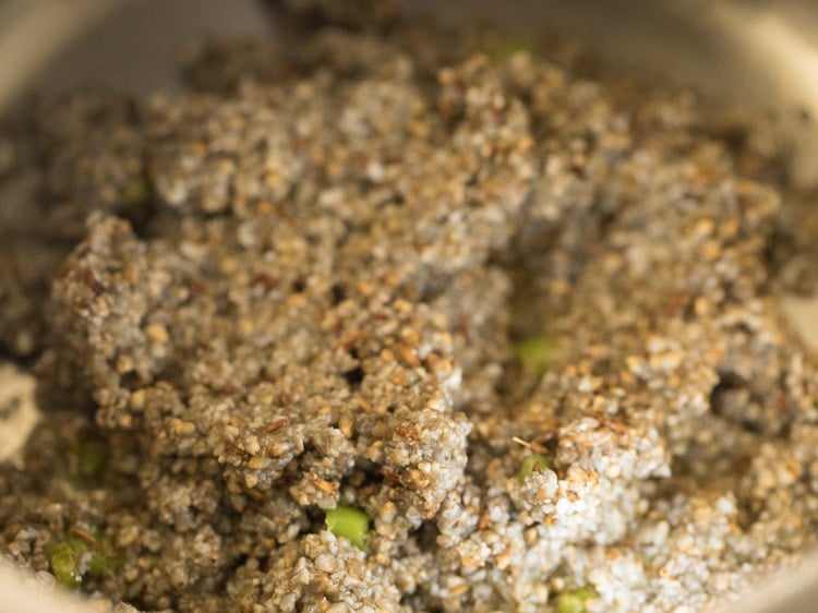 mixing the bajra with the oil and aromatics for making bajra khichdi recipe.