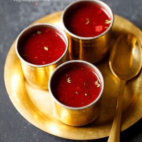 beetroot rasam served in 3 brass bowls with a spoon kept on the side on a brass plate and text layovers.