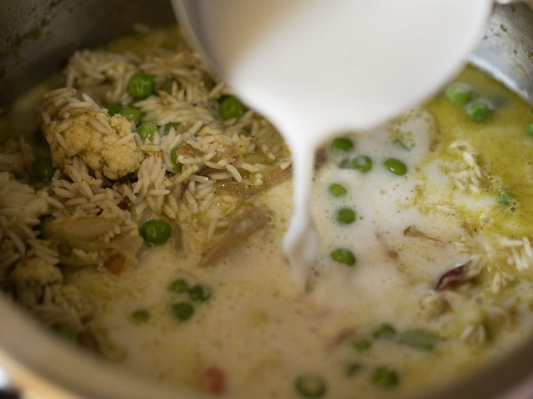 adding coconut milk to the rice-vegetable mixture. 