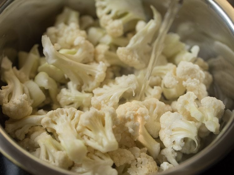 water being poured into mixing bowl filled with cauliflower florets