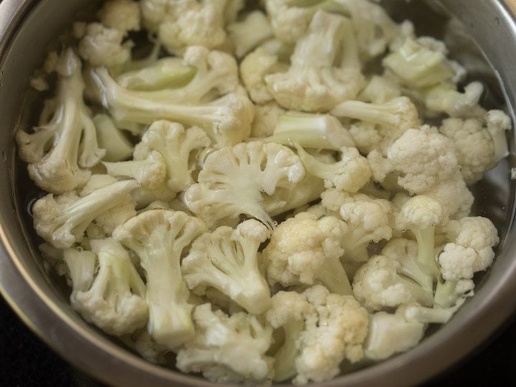 top shot of mixing bowl filled with cauliflower soaking in water