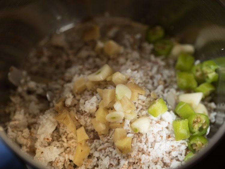 close up shot of grated coconut, chopped ginger, and chopped chilies in a mixing bowl