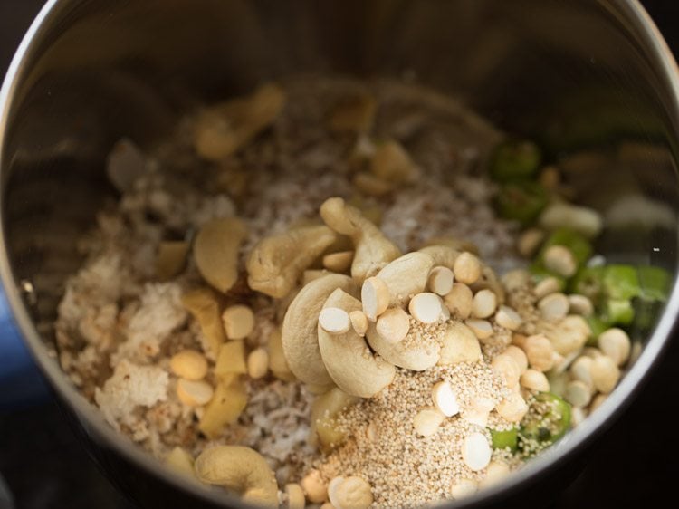 nuts being added to grated coconut and chopped chili mixture in mixing bowl