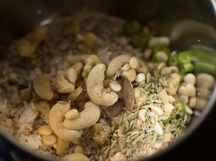 nuts being added to grated coconut and chopped chili mixture in mixing bowl