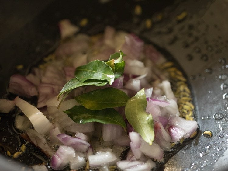 close up shot of onions and curry leaves cooking in saucepan