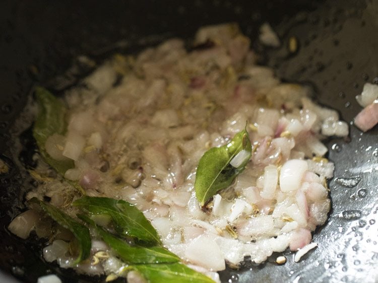 close up shot of onions and curry leaves cooking in saucepan