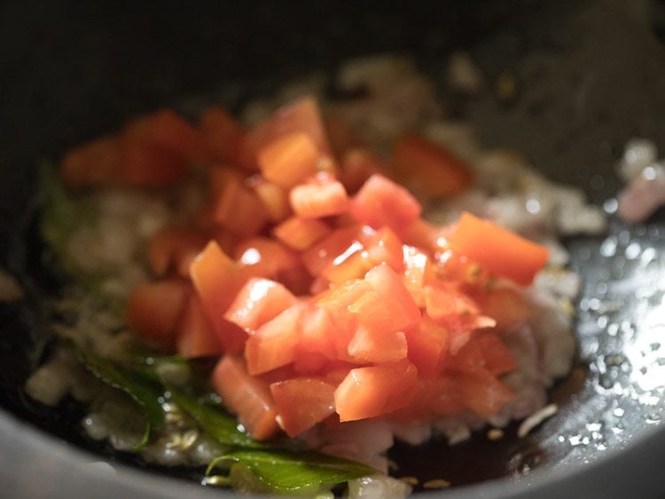 close up shot of chopped tomatoes cooking in saucepan