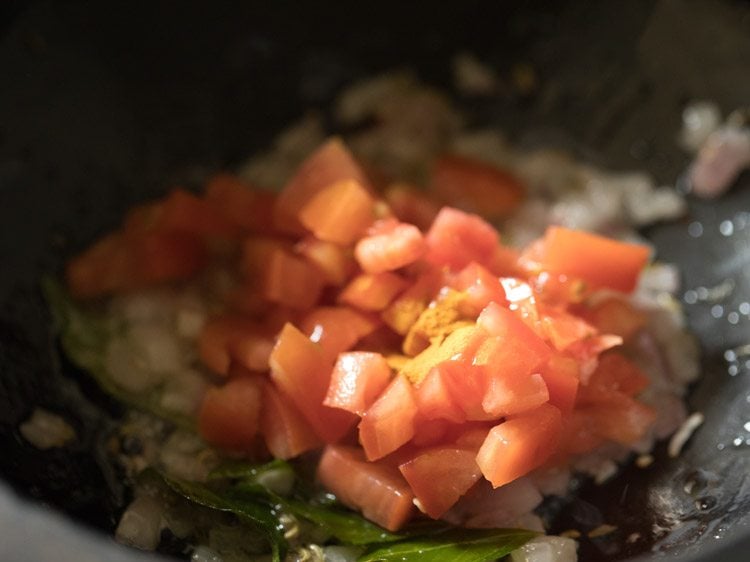 close up shot of chopped tomatoes cooking in saucepan