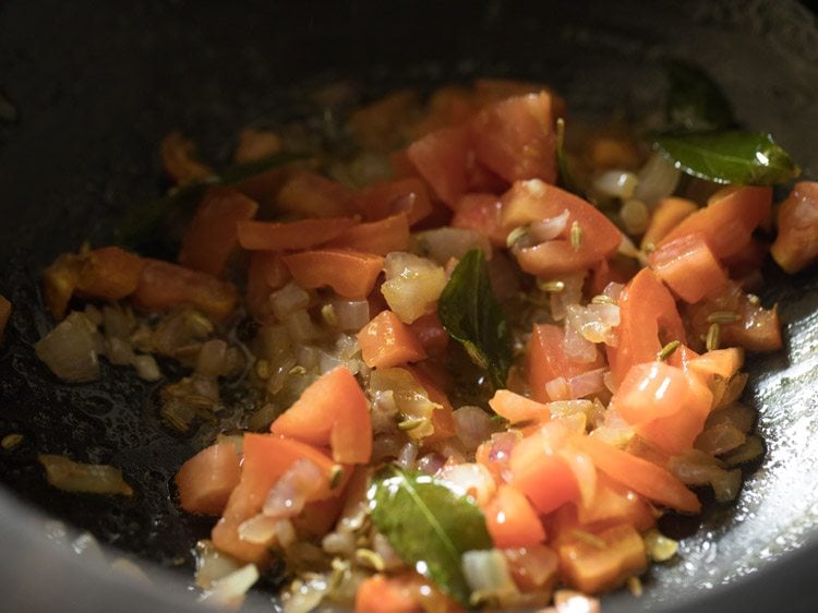 close up shot of chopped tomatoes cooking in saucepan