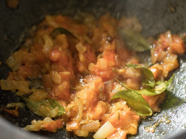 close up shot of onion and tomatoes mixture crushed up and mixed in saucepan