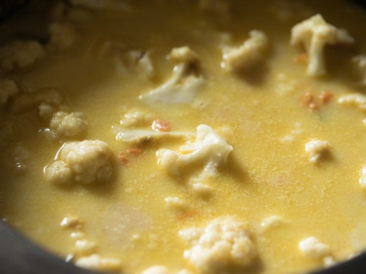 close up of water added to masala and cauliflower mixture in saucepan