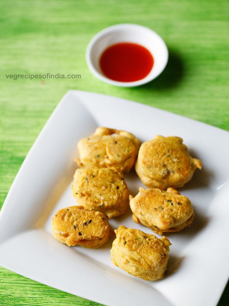 cheese pakora served on a white plate with a small bowl of tomato sauce kept in the background. 