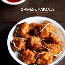 chinese pakoda garnished with cabbage shreds and served on a white plate with a bowl of schezwan sauce kept on the top left side and text layover.