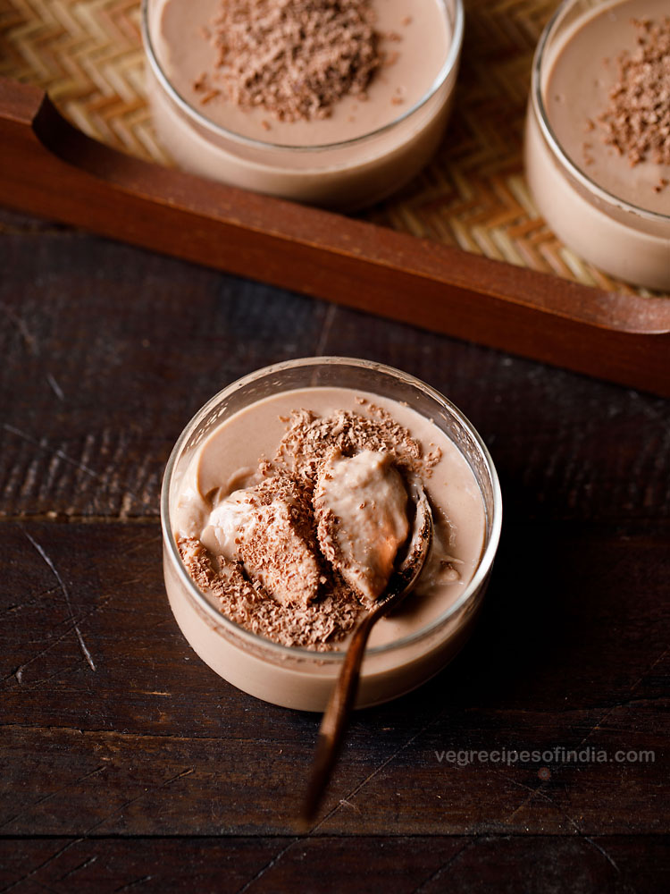 chocolate pudding in a glass bowl with a scoop in a copper spoon inside the bowl