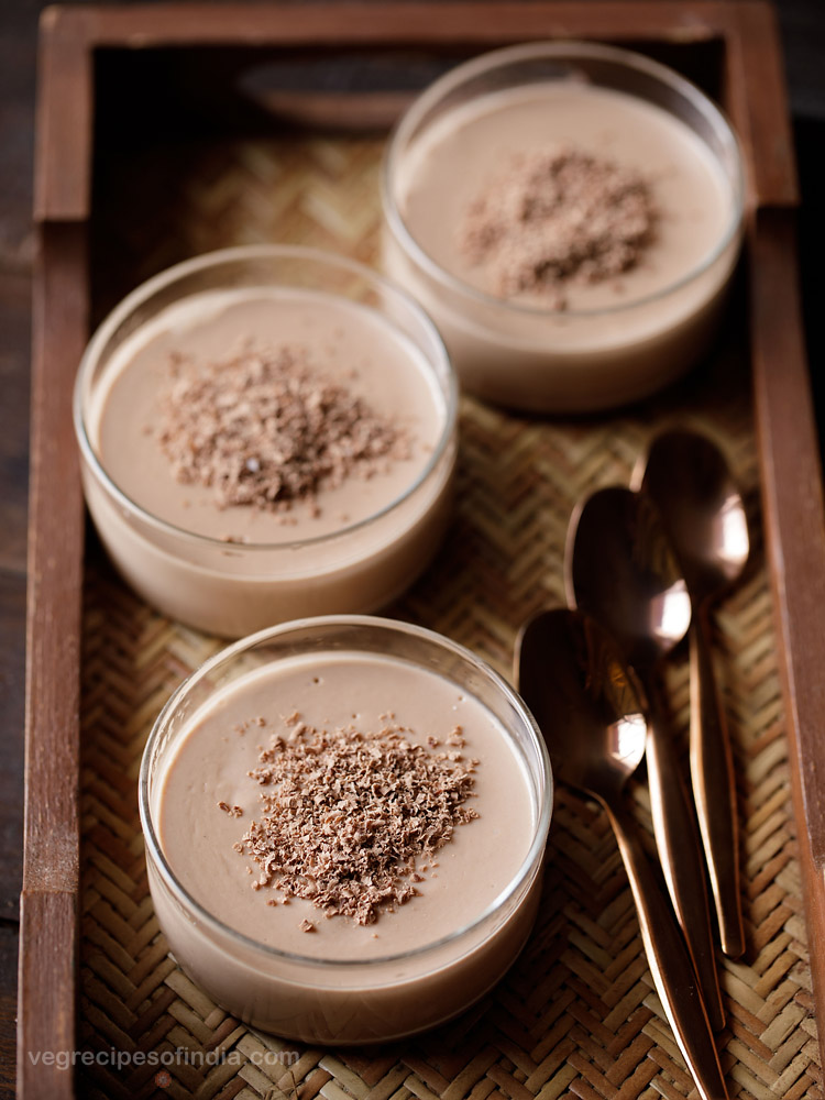 eggless chocolate in bowls topped with grated semi-sweet chocolate with three copper spoons by the side on a mat tray