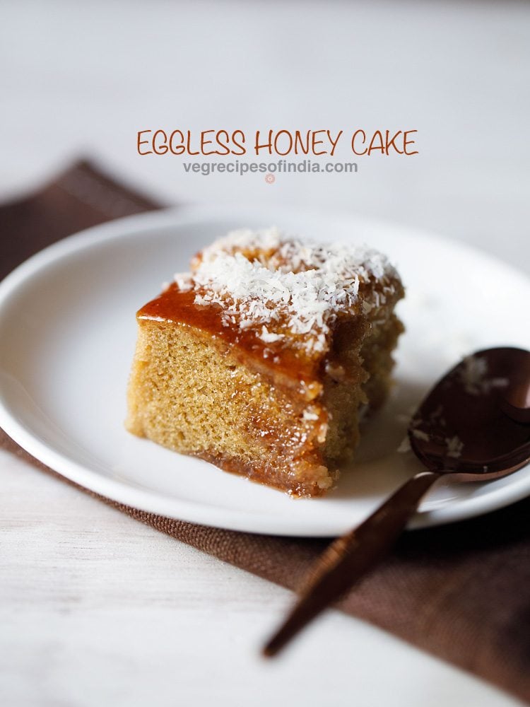 eggless honey cake slice served on a white plate with a spoon kept on right side and text layover.