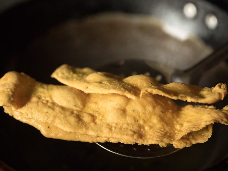 removing fried fafdas from hot oil with a slotted spoon. 