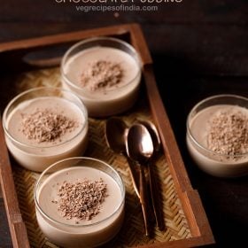 chocolate in bowls topped with grated semi-sweet chocolate with three copper spoons by the side on a mat tray