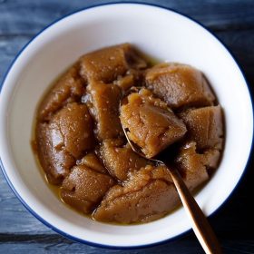 kada prashad served in a blue rimmed bowl with a spoon in it.