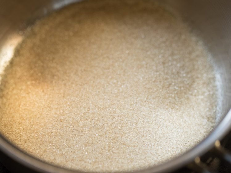 sugar added to a pan with handles for making karah prasad. 