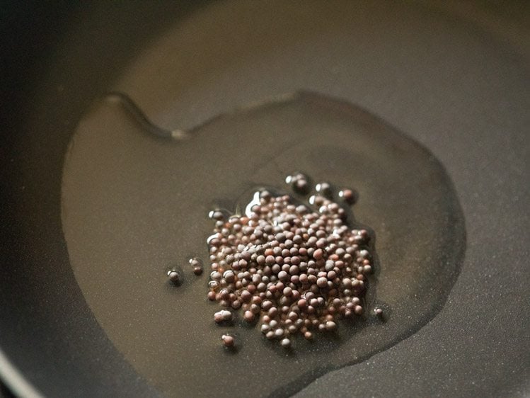 mustard seeds added to hot oil in a pan. 