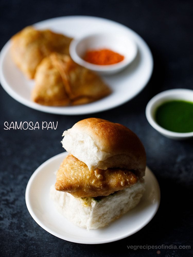 samosa pav served on a white plate with a small bowl of green chutney and a plate of samosas and garlic chutney kept in the background and text layovers.