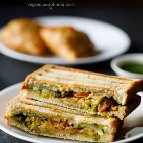 samosa sandwich served on a white plate with a small bowl of green chutney and a plate of samosas kept in the background and text layover.