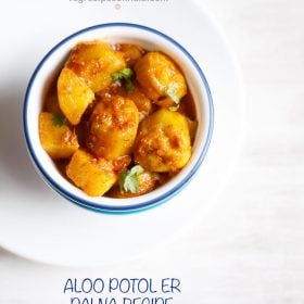 aloo potoler dalna garnished with coriander leaves and served in a blue rimmed white bowl with text layovers.