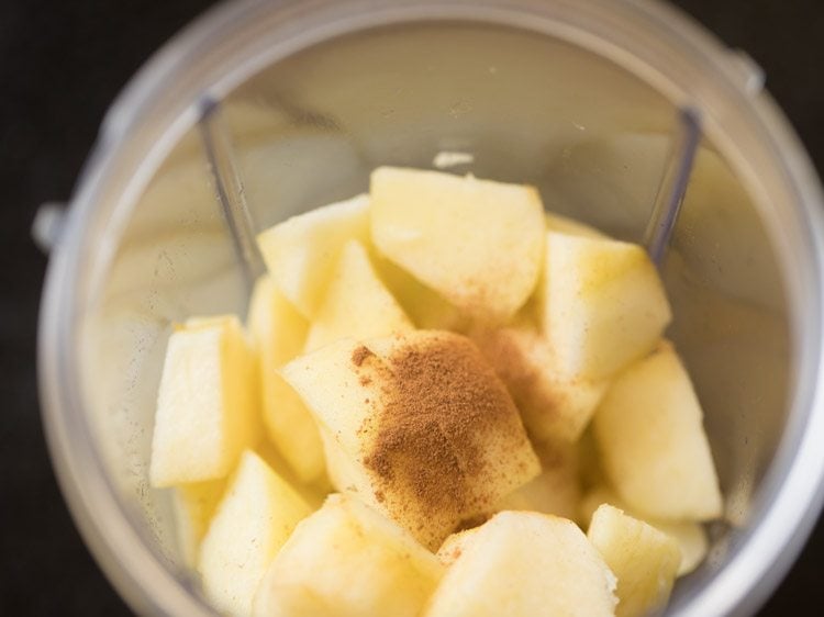 adding cinnamon powder to the chopped apples in the blender jar.