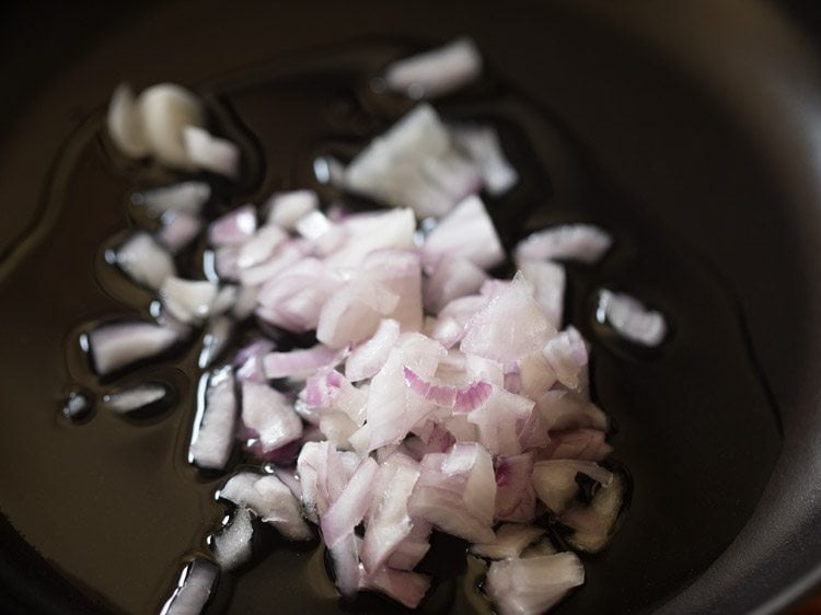Closeup shot of diced onions in oil in saucepan.