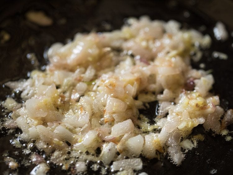 Garlic paste added to diced onions sautéing in skillet.