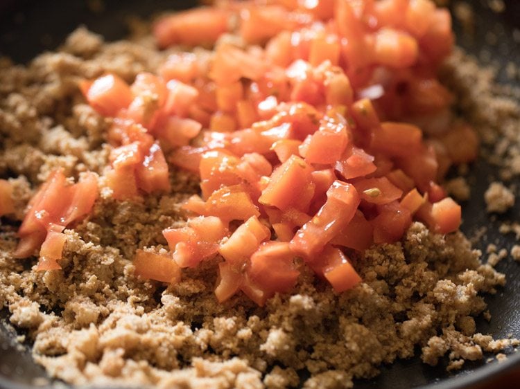 Tomatoes added to brinjal curry base cooking in skillet.