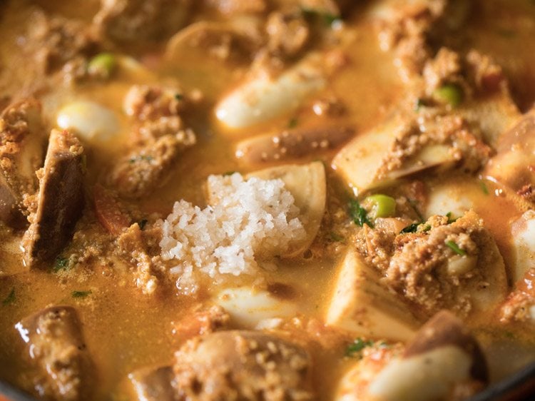 Salt added to eggplant curry mixture in skillet.