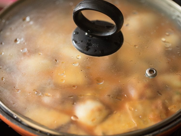 Lid covering eggplant curry to steam in skillet.