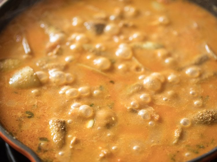 Closeup shot of baingan masala cooking in skillet.