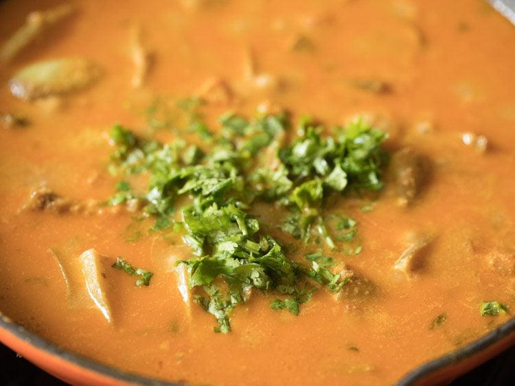 Coriander leaves added to curry in skillet.