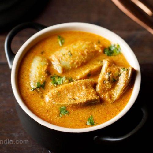 bowl of brinjal curry on a wooden table