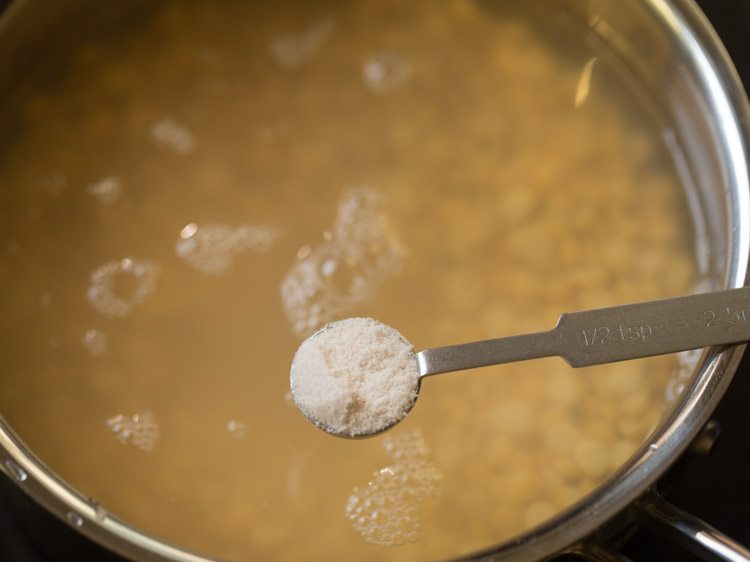 adding salt to the chana dal in pan for making kadalai paruppu sundal.