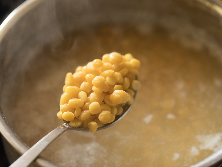 checking chana dal in a spoon while cooking. 