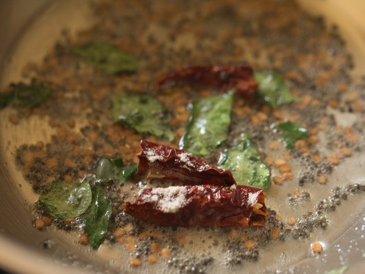 curry leaves, broken and deseeded dried red chilies and asafoetida added to the hot oil. 