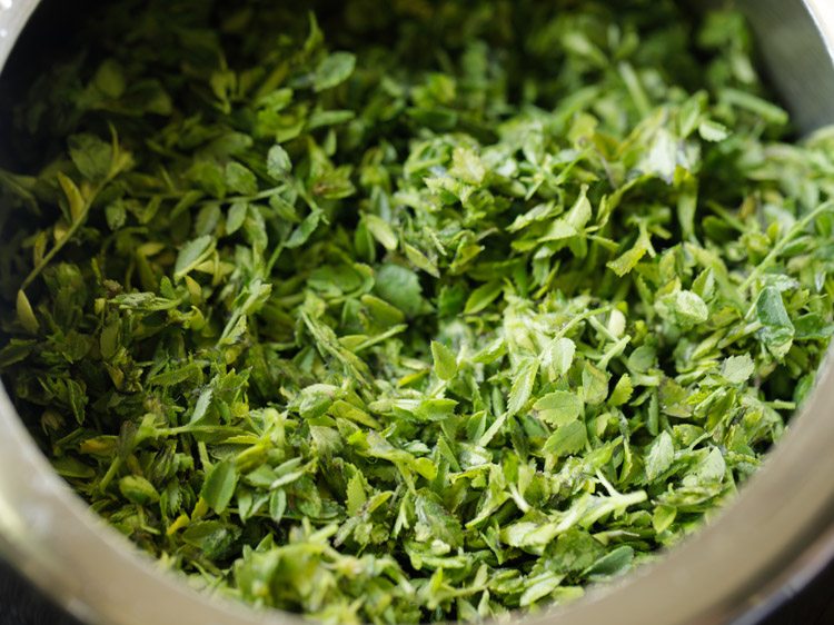 chopped saag added to a pressure cooker. 