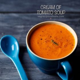 cream of tomato soup served in a large blue mug with a blue spoon kept on the side and text layovers.