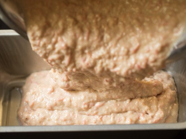 pouring eggless carrot cake batter in the prepared loaf pan