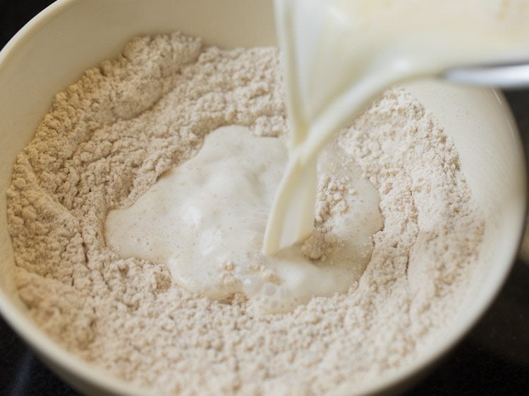 adding milk and butter mixture to dry pancake ingredients in bowl.