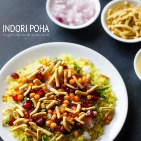 indori poha served on white plate with small bowls of chopped onions and sev kept in the top right side and text layovers.