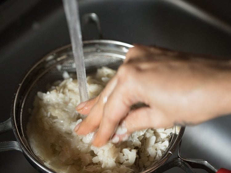 mixing and swirling poha while rinsing. 