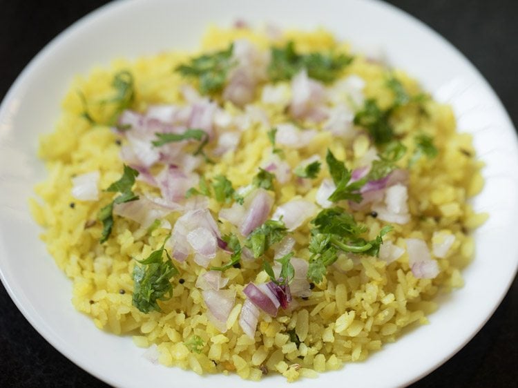 poha topped with chopped onions and chopped coriander leaves. 