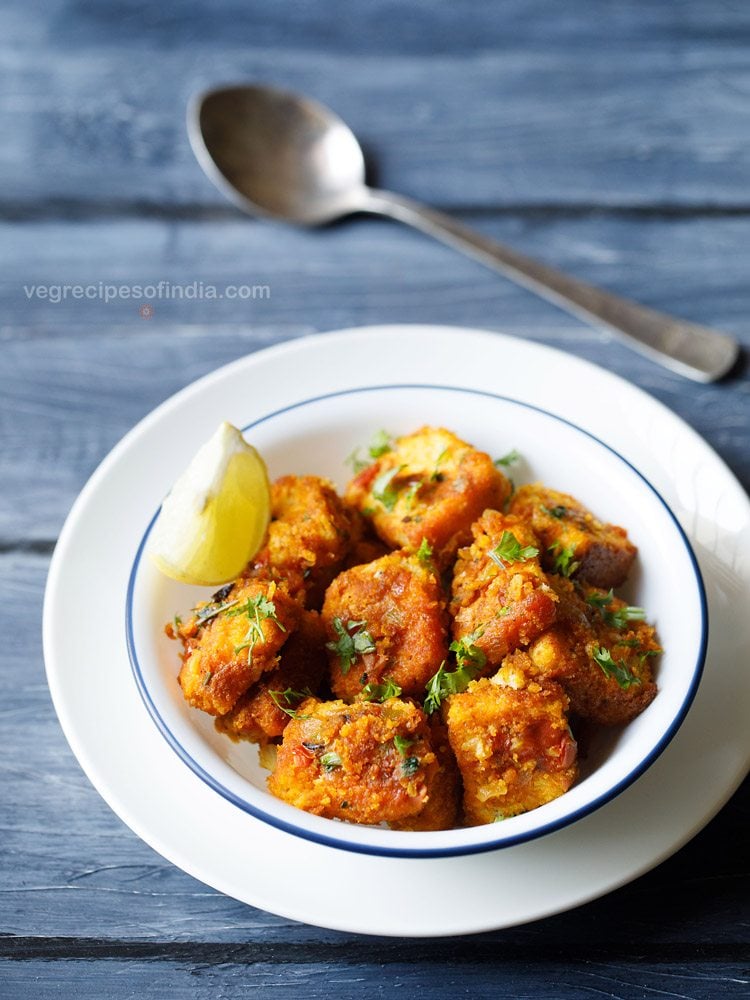 masala bread garnished with chopped coriander leaves and served in a blue rimmed bowl with a lemon wedge and a spoon kept in the background. 