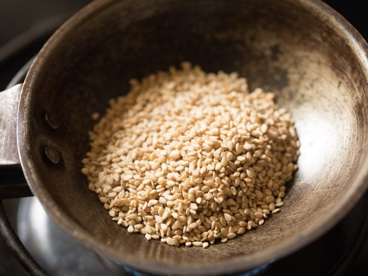 white sesame seeds added to a pan on heat. 